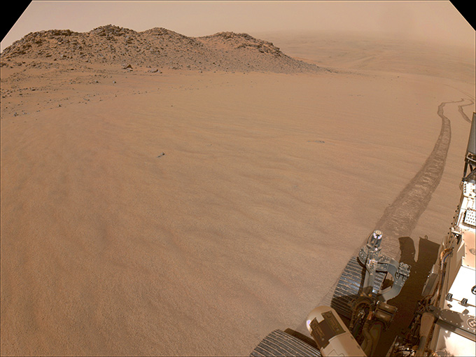 A sandy slope is presented with a part of a robot vehicle